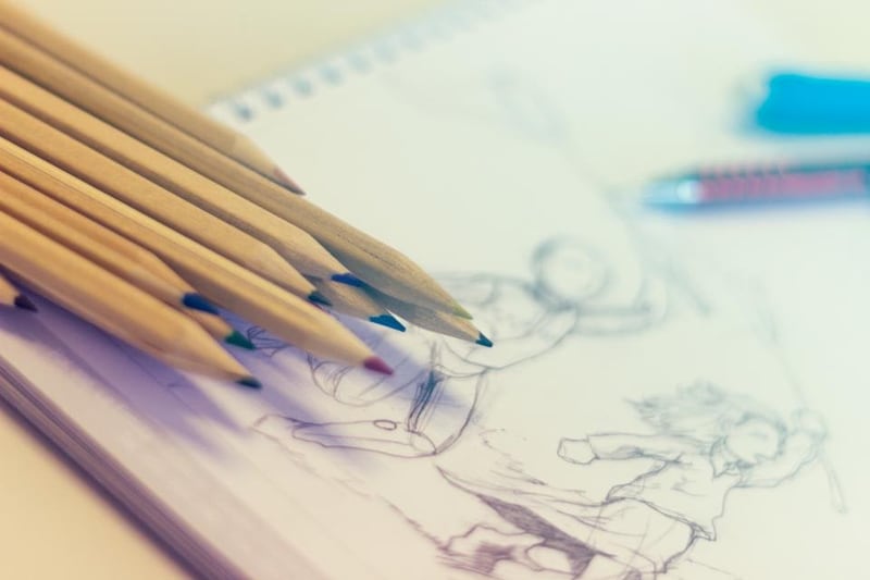Coloured pencils beside drawings on paper