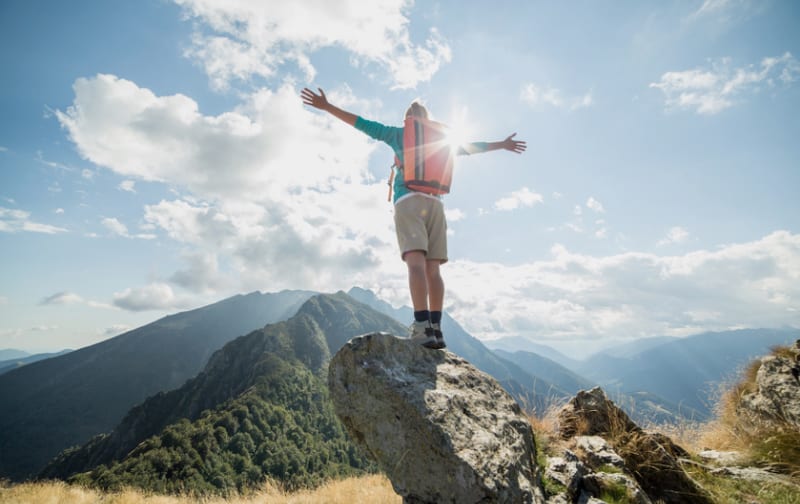 A person standing with arms outstretched on a mountain
