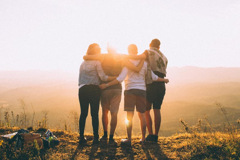 A group of friends standing together at sunset