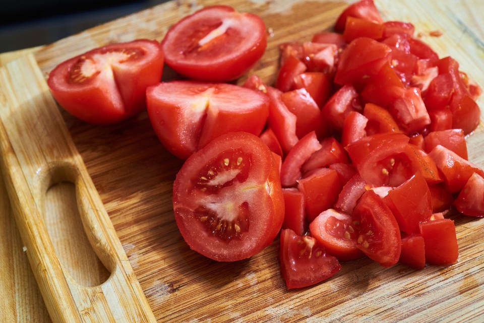 Chopped and halved tomatoes on a wooden chopping board
