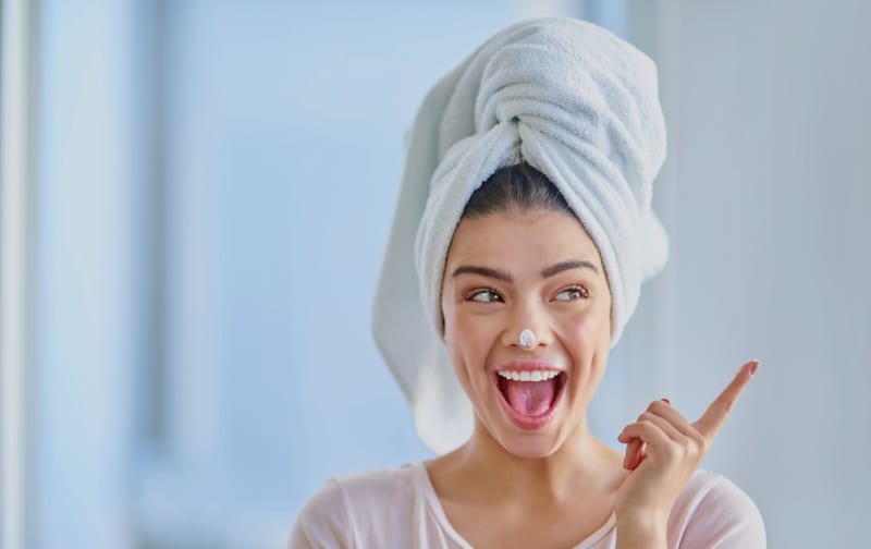 A smiling woman with a towel wrapped around her hair