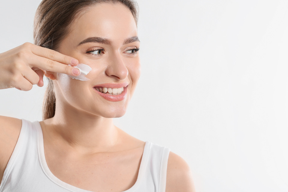 A woman gently applying cream to her cheek