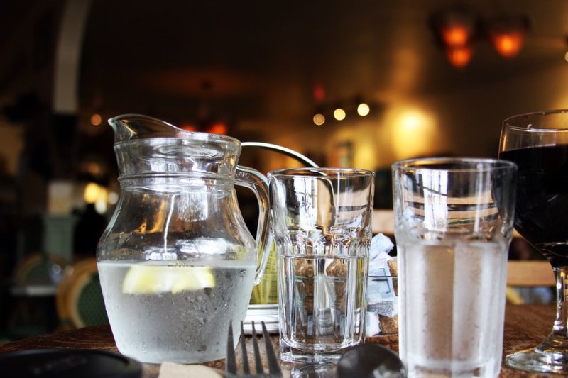 A clear water jug and drinking glasses on a table
