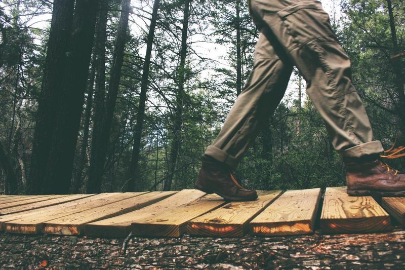A person in walking boots crossing a wooden footbridge in a forest