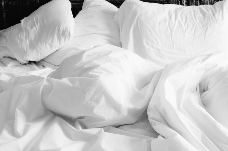 White pillows and rumpled white bedding on an empty bed